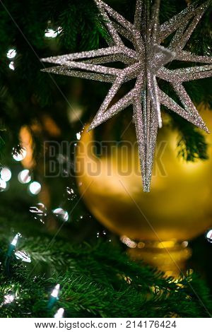 Sparkle Silver Star In Focus On Top Of Golden Ball Hang On Christmas Tree. Christmas Background