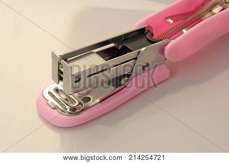 Pink colored stapler tool. Pink colored office tool.