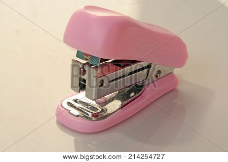 Pink colored stapler tool. Pink colored office tool.