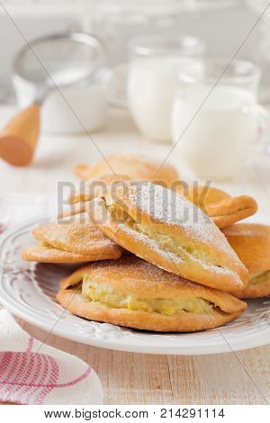 Pasties with cottage cheese and powdered sugar on a light wooden background. Traditional Russian pastry Sochnik. Selective focus. .