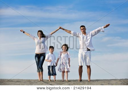 happy young family have fun on beachand showing home sign with conncected hands while protecting childrens