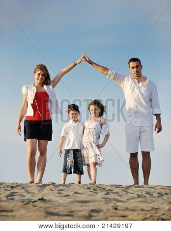 happy young family have fun on beachand showing home sign with conncected hands while protecting childrens