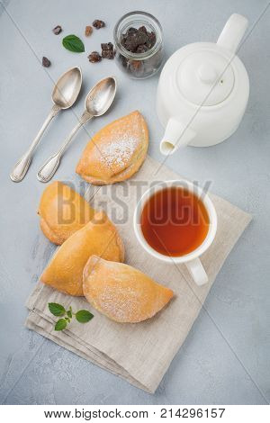 Pasties with cottage cheese and powdered sugar on a gray stone or concrete background. Traditional Russian pastry Sochnik. Selective focus. Top view.