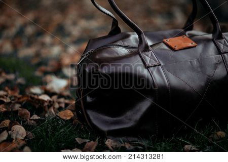 black eather bag in bright colorful summer grass in the park