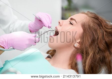 Profile close up of a young woman wearing braces getting dental examination at the clinic health medicine smile teeth dentistry beauty lifestyle youth people professionalism trust treatment.