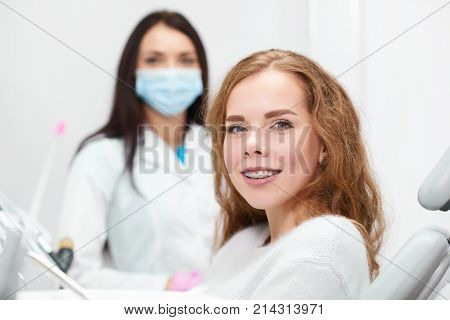 Happy red haired young woman smiling to the camera wearing braces her dentist posing on the background copyspace medical treatment appointment medicine healthcare dentistry teeth.