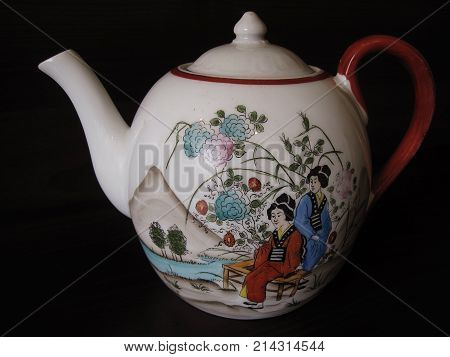 White ceramic teapot with geishas in garden near mauntain