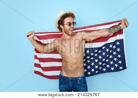 Smiling shirtless muscular man in hat with USA flag.