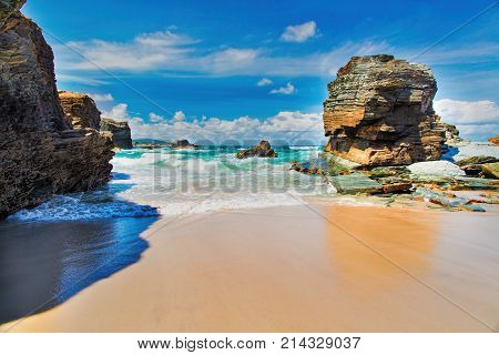 View of the ocean between rocks of Praia de Augas Santas. A fragment of the beach of cathedrals in summer day in good weather