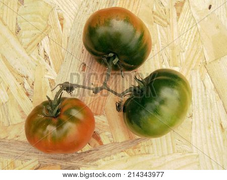 Tomatoes on a table in contrast colors green, red, black and white. Harvest of autumn background or texture for fall theme. Symbol or sign of odds, vary and discrepancy. Flat layout view