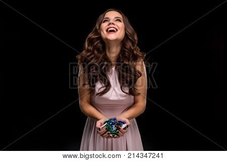 Female Poker player with paint black nails hold her poker chips to make a bet. Gambling and casino business concept. Studio shot on a black background. Casino