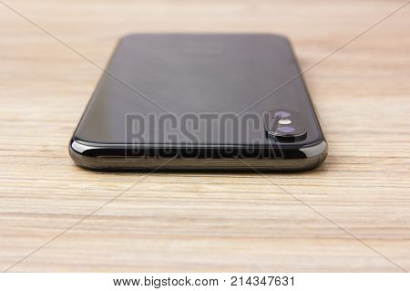 Dual camera smartphone. A popular smartphone rests on a wooden table.