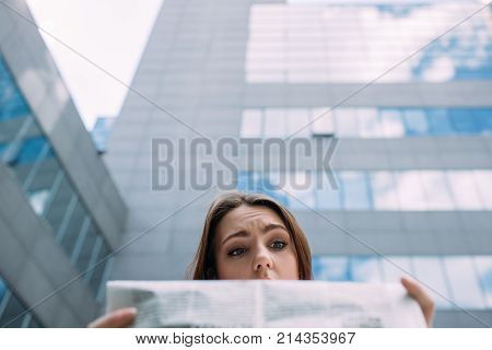 puzzled confused perplexed bewildered woman reading newspaper concept