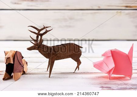 Animal figurines on wooden background. Finished lion, deer, pig origami models for school exhibition. Arts and crafts.