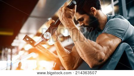 Strong ripped man training bicepses in gym