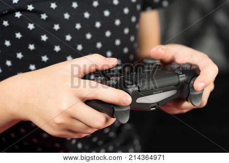 UFA RUSSIA - NOVEMBER 12 2017: Hand girl playing Sony Dualshock 4 controller for PlayStation 4 pro. Sony PlayStation 4 pro game console of the eighth generation.
