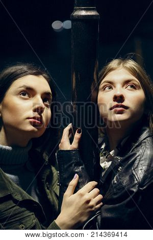 Closeup Of Two Beautiful Caucasian Teenage Girls Outdoors .night Portrait In Lights Of Lamp Pillar.