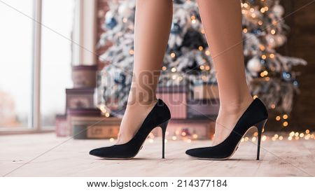 Pretty legs in beautiful high heel shoes with a Christmas gifts and New Year's Tree. New Year's party 2018. Christmas Eve.
