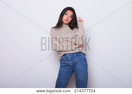 Fashion posing beautiful Asian girl in trendy wearing. Casual wearing in jeans, high heel shoes and sweeter