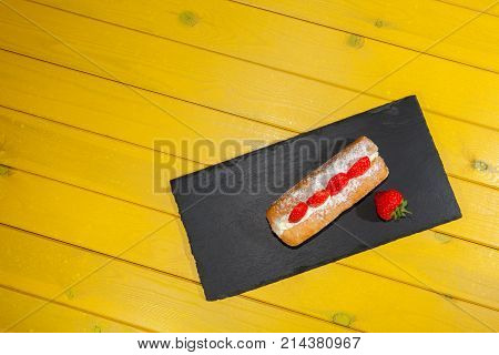 Strawberry cake on yellow table. Bright colorful food art image. Colourful sugary doughut. Delicious donut vibrant summer color dessert.