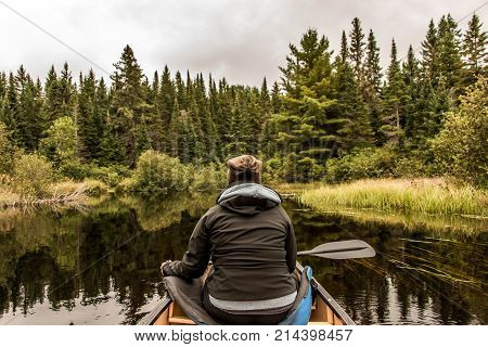 Girl canoeing with Canoe on the lake of two rivers in the algonquin national park in ontario Canada on a cloudy day