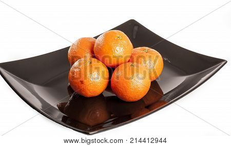 Mandarin orange. Pile of oranges mandarins on plack plate and isolated white studio background. Food photo.