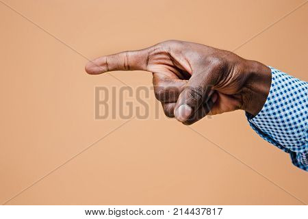 Black male hand point finger. Hand gestures - man pointing on virtual object with forefinger, isolated on brown background