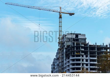 unfinished building construction and building cranes against clear blue sky background.