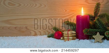 Avent candle and Christmas cookies isolated on wood background. Christmas background with snow, candle and fir-tree branch.