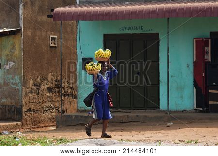 Kampala Uganda - Aug 26 2010: Local woman carries bananas in slum of Kampala. Nearly 40% of slum dwellers have a monthly income of just 2500 shillings less than a dollar