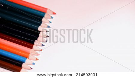 Multicolored pencils on the table. A stack of colored pencils tied together. A scattering of writing supplies and stationery.