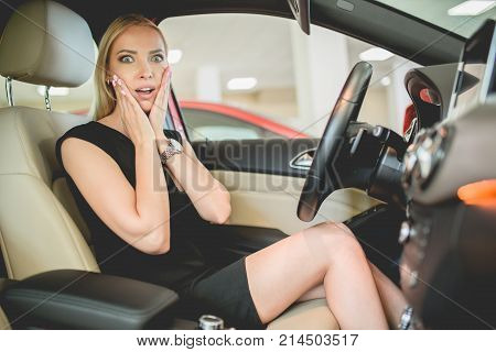 Beautiful woman on front seat of new electo car. Woman impressed by new vehicle.
