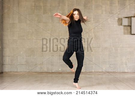 Pretty girl in black is dancing. Young beautiful dancer woman performing modern dance on studio background. Skillful modern dance performer.