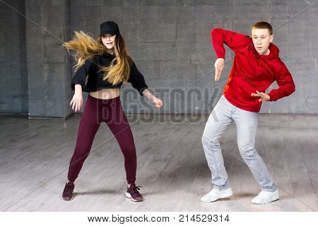 Attractive couple dancing hip-hop. Skillful modern style teenagers dancing contemporary dance on studio background.