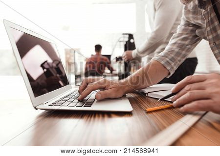 Three men set up a self-made 3d printer to print the form. They check the scribes of the 3d printer on the laptop. An elderly man directs the process of starting and printing a printer.