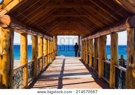 A man or woman looking at the see at the bottom of a bridge