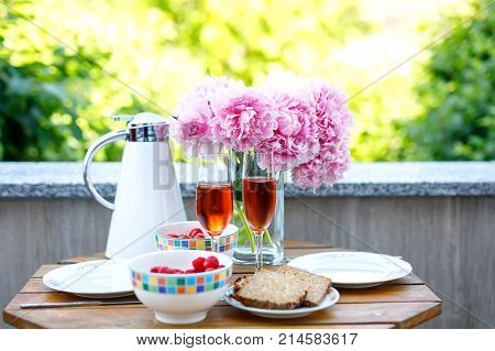 Breakfast table with bread, frest vegetables and berries, coffee and champagne served on balkony or hotel on summer morning.