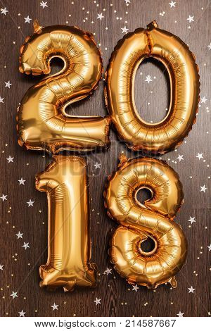 Bright gold balloons figures 2018, New Year Balloons with glitter stars on dark wood table background. Christmas and new year celebration