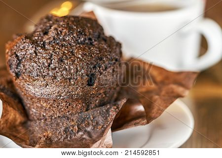 Delocious chocolate muffin with a cup of tea on the wooden table close up