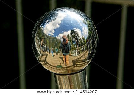 metal sphere that reflects the image of a young photographer