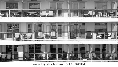 sruise sgip with chairs and tables has glass windows and handrail of residential building with nobody sunny day on exterior background