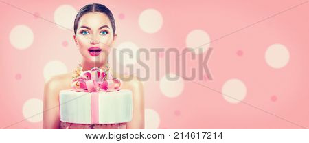 Beauty fashion model girl holding Beautiful Big Cake. Funny joyful styled woman with wedding, party or birthday cake on pink background. Diet, dieting concept. Junk food, Slimming, weight loss. Wide.