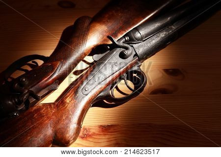 Ancient hunting shotguns closeup on wooden board under light beam