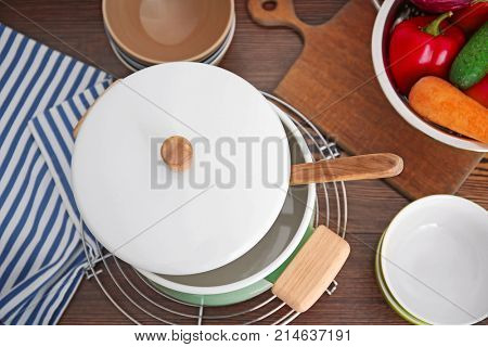 Stewpan, bowls and vegetables on wooden table