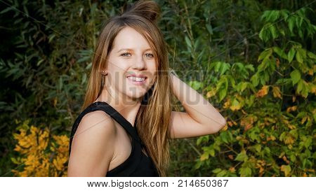 Pretty Beautiful Girl in Black Shirt Posing in the Park During Sunset in Warm Day on Green and Yellow Trees Background