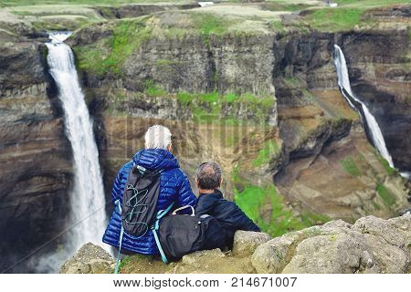 famous Haifoss waterfall in southern Iceland. treking in Iceland. elderly hikers sitting on the edge of a cliff and looking at waterfall