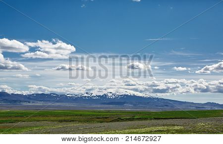 Travel to Iceland. road in a bright sunny mountain landscape. Vatna volcano covered with snow and ice on tne background.