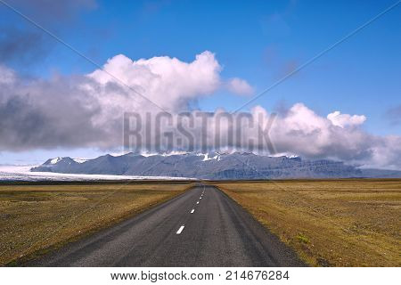 Travel to Iceland. road in a bright sunny mountain landscape. Vatna volcano covered with snow and ice on tne background.