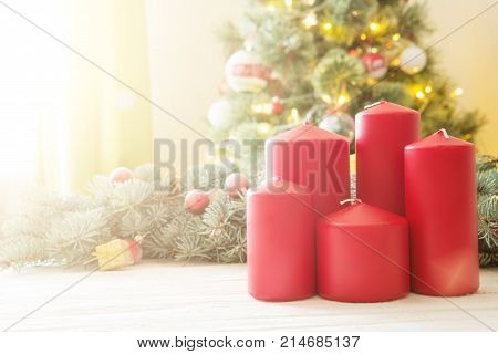 Red Christmas Candles On White Wooden Plank Against Christmas Tree In Living Room