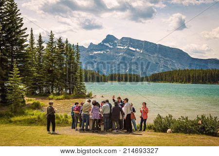 TWO JACK LAKE, ALBERTA, CANADA - JUNE 26, 2017 : Group of Asian tourists having lunch at the two jack lake in Banff National Park with Mt. Rundle in the background.